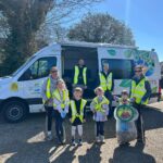 adults and children in high viz jackets with litter pickers in front of a van ready to go on a litter pick